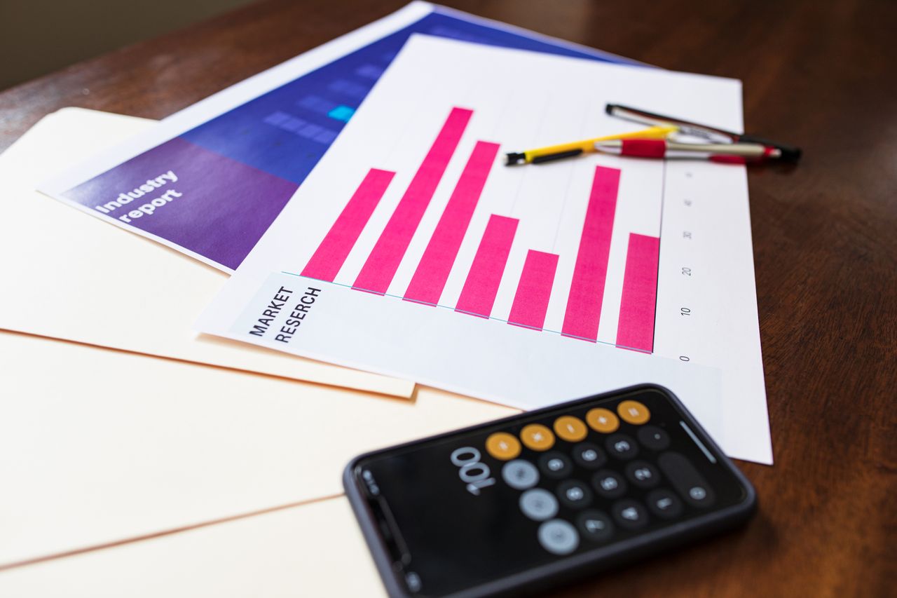 who-we-are An illustrative market research chart and calculator on a wooden desk for business analysis.
